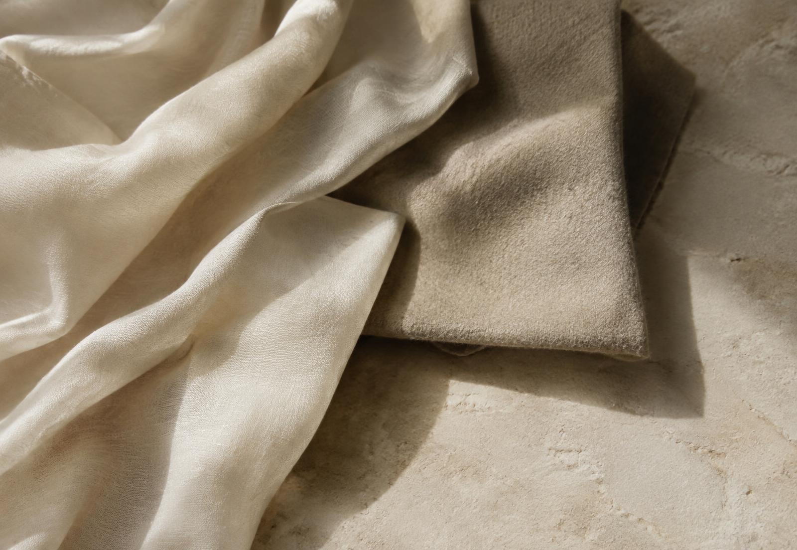 Layered ivory and stone fabric swatches on limestone